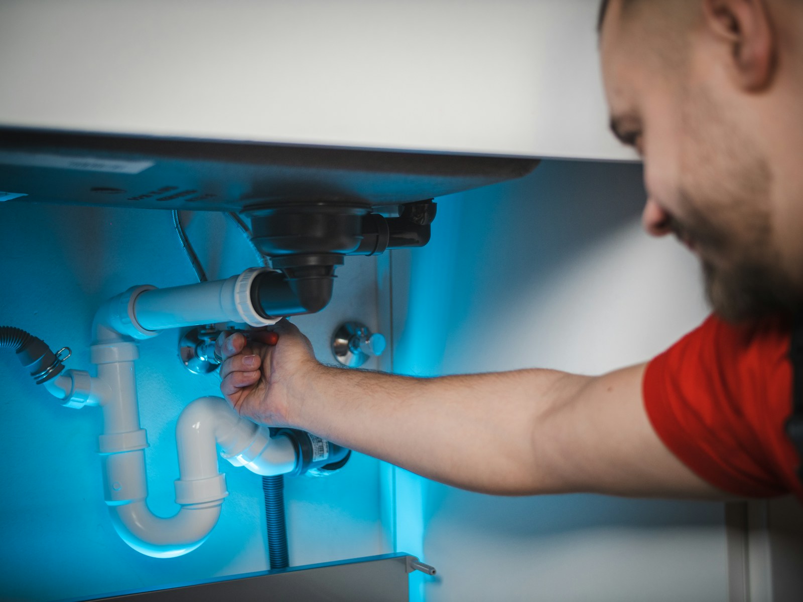 Professional adjusting pipework beneath a sink